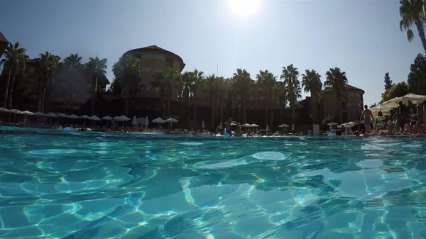 Aileleri olan turistler açık havuzun kıyısında dinleniyorlar. Suyun üzerinde çekim yapmak