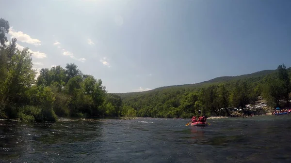 Rafting için ekipman ve teçhizatlı bir grup insan kauçuk bir tekneyle dağ nehrinde yüzüyorlar.