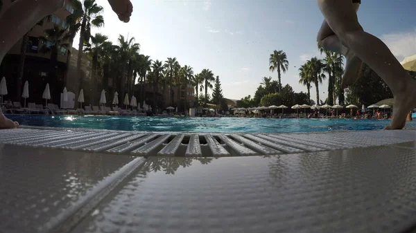 Çocuklar koşa koşa havuza atlıyor.