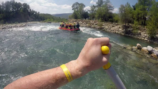 Kürekçi bir kürekle kayalıklara oturmadan tekneyi dengelemeye çalışıyor.