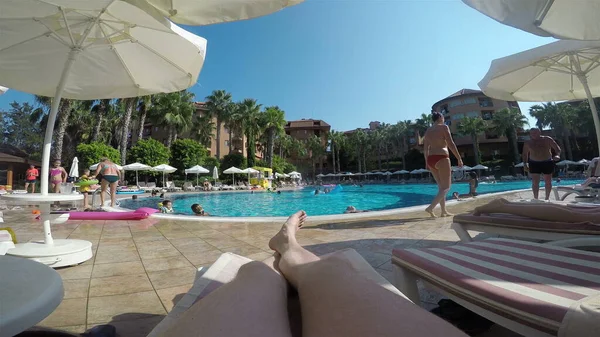 Şezlonga uzanmış çıplak bacaklar açık havuza doğru uzanıyor.