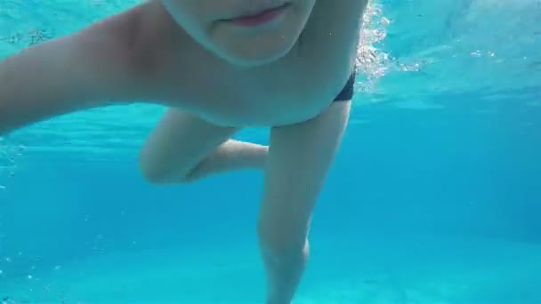 Um menino em óculos de natação posa para a câmera subaquática — Vídeo de Stock