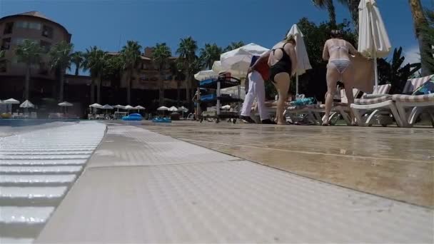 The service staff collects empty dishes from tables near the pool — Stock Video