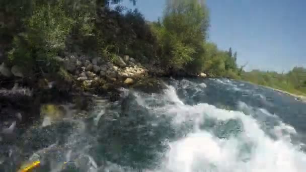 La corriente del río de la montaña da la vuelta al barco y lo lava en la orilla rocosa — Vídeos de Stock