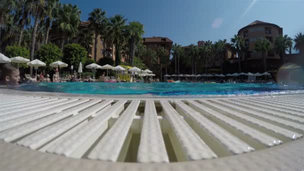 Lidé plavou v bazénu a opalují se na lehátkách pod slunečníky — Stock video