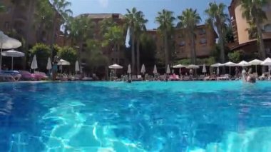 Ağzında düdük olan bir Aqua aerobik koçu karada egzersiz gösteriyor.