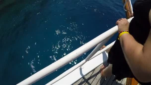少女はヨットのデッキにある手すりにしがみついて海を賞賛しています — ストック動画