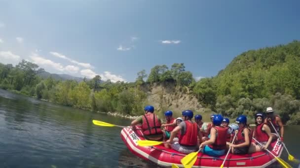 A tripulação está equipada em um barco inflável de borracha envolvido em rafting em um rio de montanha — Vídeo de Stock