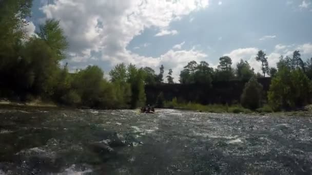 Un bateau avec un groupe de personnes flotte le long d'un lit de rivière pierreux encombré de débris — Video