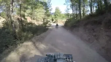 Dörtlü bisikletli sporcular, yüksek hızda tozlu bir yolda yolun üstesinden geliyorlar.