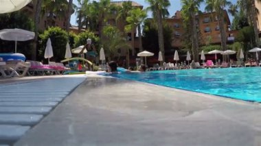 Aqua aerobik sınıfındaki fitness eğitmeni havuzda tatilciler için egzersizler gösteriyor.