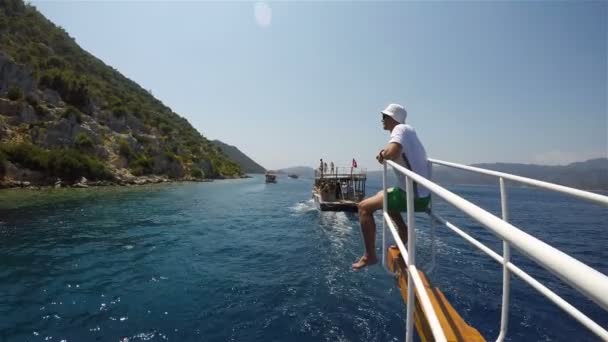 Un hombre se sienta en la proa de un crucero durante un viaje en barco frente a la costa de Turquía — Vídeos de Stock