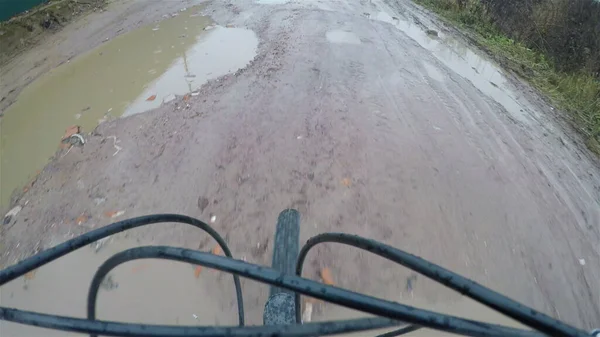 Bir bisikletçi taşra yolundaki su birikintilerinin ve deliklerin etrafında dolaşır. Birinci şahıs vuruldu.