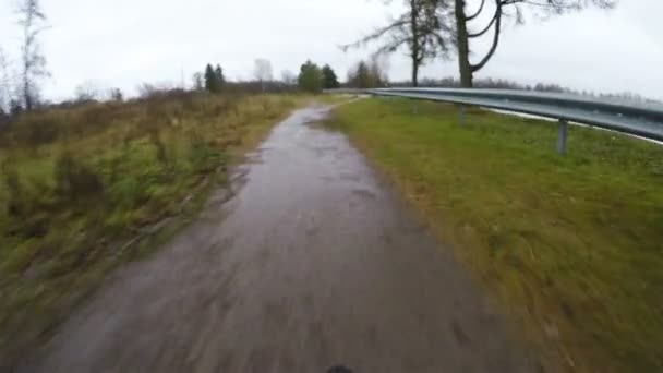 Een fietser rijdt met hoge snelheid over een kleine brug bij het meer en stopt — Stockvideo