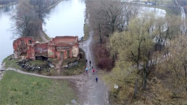Mensen met honden lopen langs een verwoest oud stenen gebouw — Stockvideo