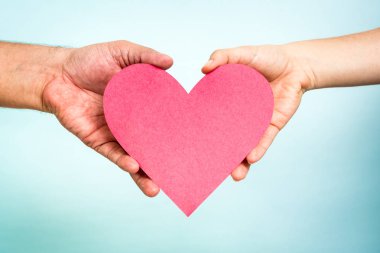 Kalp şekli mavi zemin üzerine kırmızı kağıt tutan iki eli seviyorum.