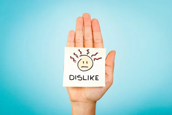 Dislike emoticon note on hand with blue background — Stock Photo, Image