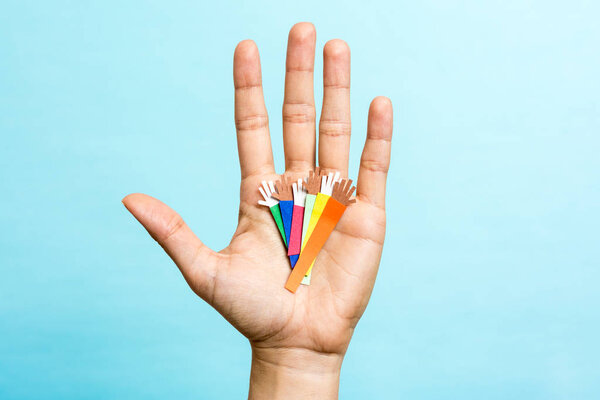 Hand up showing group of diverse multicolors paper hands on blue background. Multiracial concept.