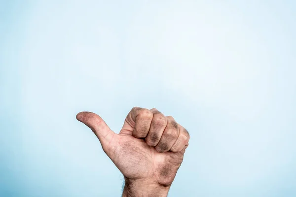 Een man vuile hand maken duim omhoog gebaar op blauwe achtergrond — Stockfoto