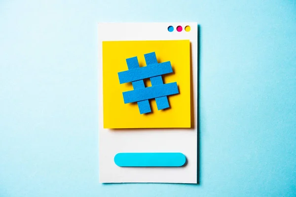 Хештег символ записка с концепцией бумажного смартфона на синий — стоковое фото