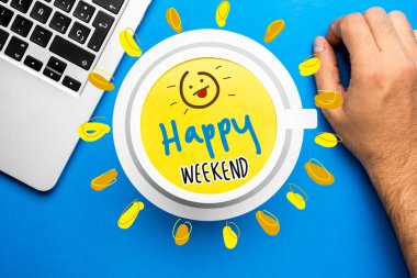 Happy weekend quote and coffee cup on blue background with lapto