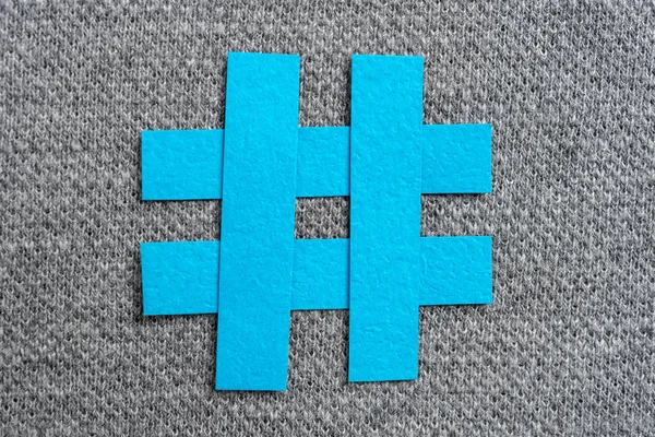 Blue hashtag symbol made with blue paper on a fabric and texture — Stock Photo, Image