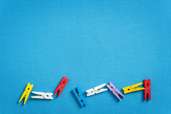 Маленькая разноцветная деревянная одежда на синей фактуре — стоковое фото