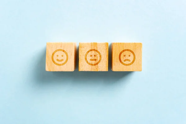 Szczęśliwa, neutralna i zmarszczona twarz na drewnianych klockach zabawki i niebieski backg — Zdjęcie stockowe