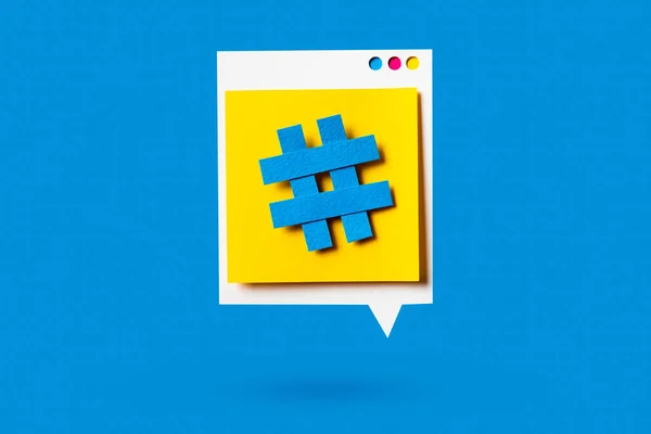 Paper cutout of hashtag symbol on a yellow speech bubble on blue