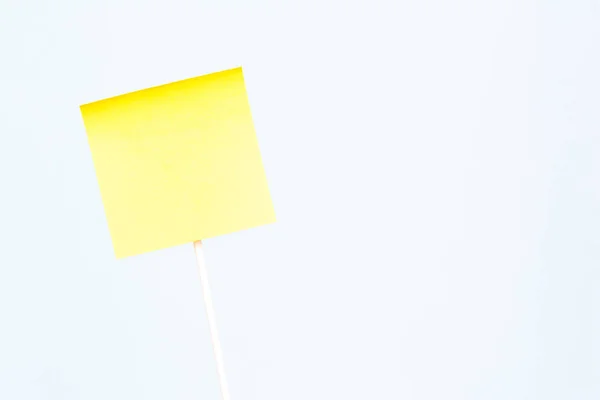 Uma nota de papel amarelo adesivo sobre vara e fundo azul. Emp. — Fotografia de Stock