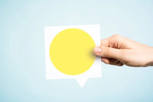 Woman holding a speech bubble with a yellow circle on blue backg — Stock Photo, Image