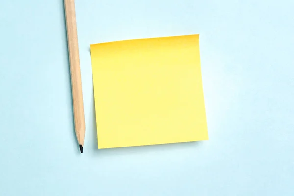 Κίτρινο κενό μήνυμα κενό χαρτί με ένα μολύβι σε μπλε backgroun — Φωτογραφία Αρχείου