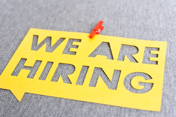 "WE ARE HIRING". Yellow speech bubble banner on blank gray textu — 스톡 사진