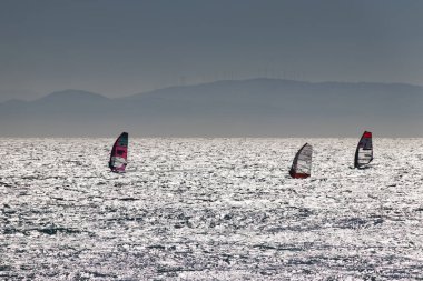 Tarifa, İspanya. 3 Şubat 2020. Birçok rüzgar sörfçüsü Atlantik Okyanusu 'nda rüzgarlı Bolonya plajı yakınlarında ve arka planda Afrika dağları var.