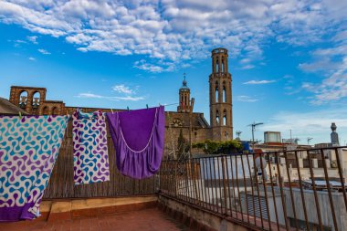 Barselona, İspanya. 26 Nisan 2020 'de. İspanya 'daki koronavirüs tecridi sırasında etrafını palyaçoların sardığı Santa Maria del Mar katedrali yakınlarındaki bir çatıda asılı giysiler.