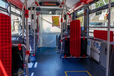 Barselona, İspanya. 26 Nisan 2020 'de. Sürücü için plastik korumalı boş otobüs ve covid krizi sırasında sosyal mesafeye ilişkin uyarı işaretleri