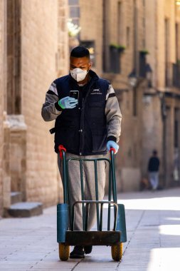 Barselona, İspanya. 29 Nisan 2020 'de. Coronavirus tecridi sırasında yolda boş bir araba taşıyan teslimatçı.