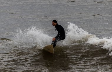Barselona, İspanya. 9 Mayıs 2020. Barceloneta sahilinde sörf yapan bir adam. Sahilde spor faaliyetlerine sadece sabah 6-10 arası izin veriliyor ve plaja giriş polis tarafından kontrol ediliyor..