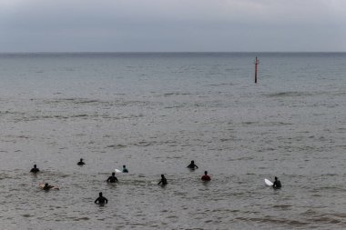 Barselona, İspanya. 9 Mayıs 2020. Barceloneta sahilinde bulutlu bir sabahta dalgaları bekleyen sörfçüler. Sahilde spor faaliyetlerine sadece sabah 6-10 arası izin veriliyor ve plaja giriş polis tarafından kontrol ediliyor..