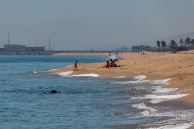 Canet de Mar, İspanya. 20 Mayıs 2020. Kapalı kapılar ardında Maresme bölgesindeki boş bir Sant Pol de Mar plajında yatan insanlar