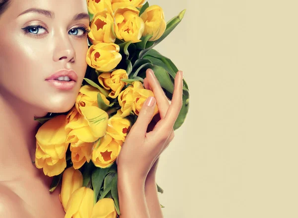 Brunette woman holding yellow tulips — Stock Photo, Image