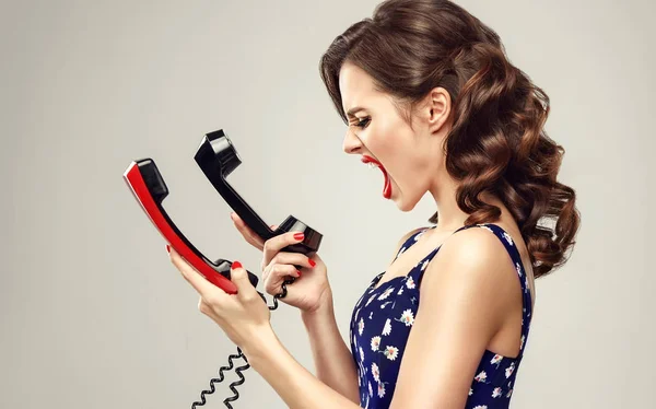 Раздраженная девушка со старыми телефонами — стоковое фото