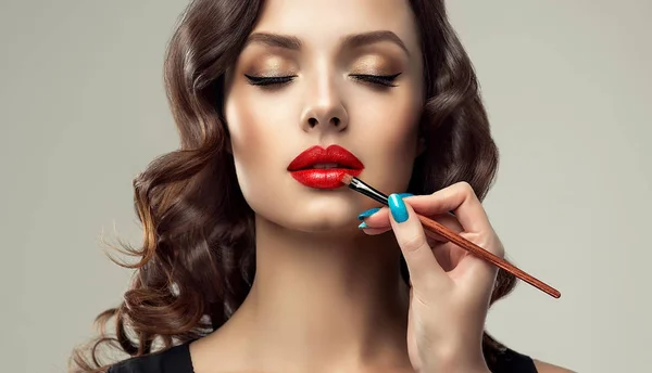 Maquillaje artista aplica lápiz labial rojo — Foto de Stock