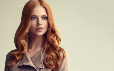 Kızıl saçlı kız uzun ve parlak kıvırcık saçlı. Güzel model kadın kıvırcık saç modeli ile. Bakım ve güzellik saç