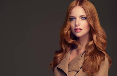 Kızıl saçlı kız uzun ve parlak kıvırcık saçlı. Güzel model kadın kıvırcık saç modeli ile. Bakım ve güzellik saç