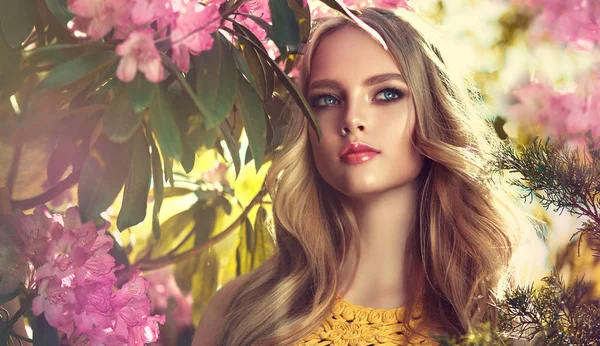 美丽的春天模型女孩在芬芳的花朵在夏天开花公园 女人在一个盛开的花园 化妆品和香水 卷发金发 — 图库照片