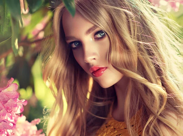 美丽的春天模型女孩在芬芳的花朵在夏天开花公园 女人在一个盛开的花园 化妆品和香水 卷发金发 — 图库照片