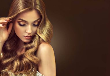 Uzun ve parlak kıvırcık saçlı esmer kız. Güzel model kadınla dalgalı saç modeli. Bakım, kozmetik ve güzellik