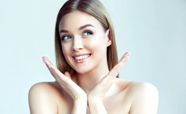 Mutlu güzel kız tarafına bakarak bir kahkaha ile yanaklarının tutarak. Etkileyici yüz ifadeleri. Kozmetik ve Spa, cilt bakım modeli