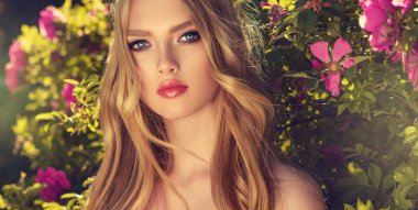 Yaz çiçeği Park kokulu pembe çiçekler güzel bahar kız. Kadın bir çiçek bahçesinde. Moda, kozmetik ve parfümler. Kıvırcık sarı saçlı